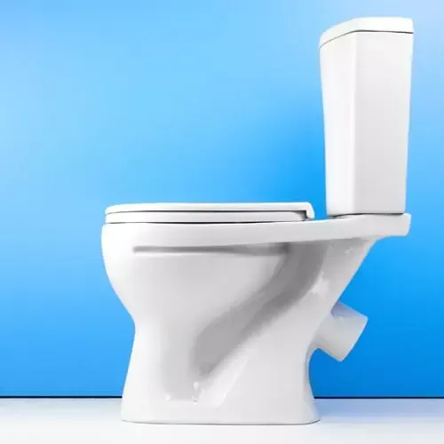 A white toilet is sitting in front of a blue wall.