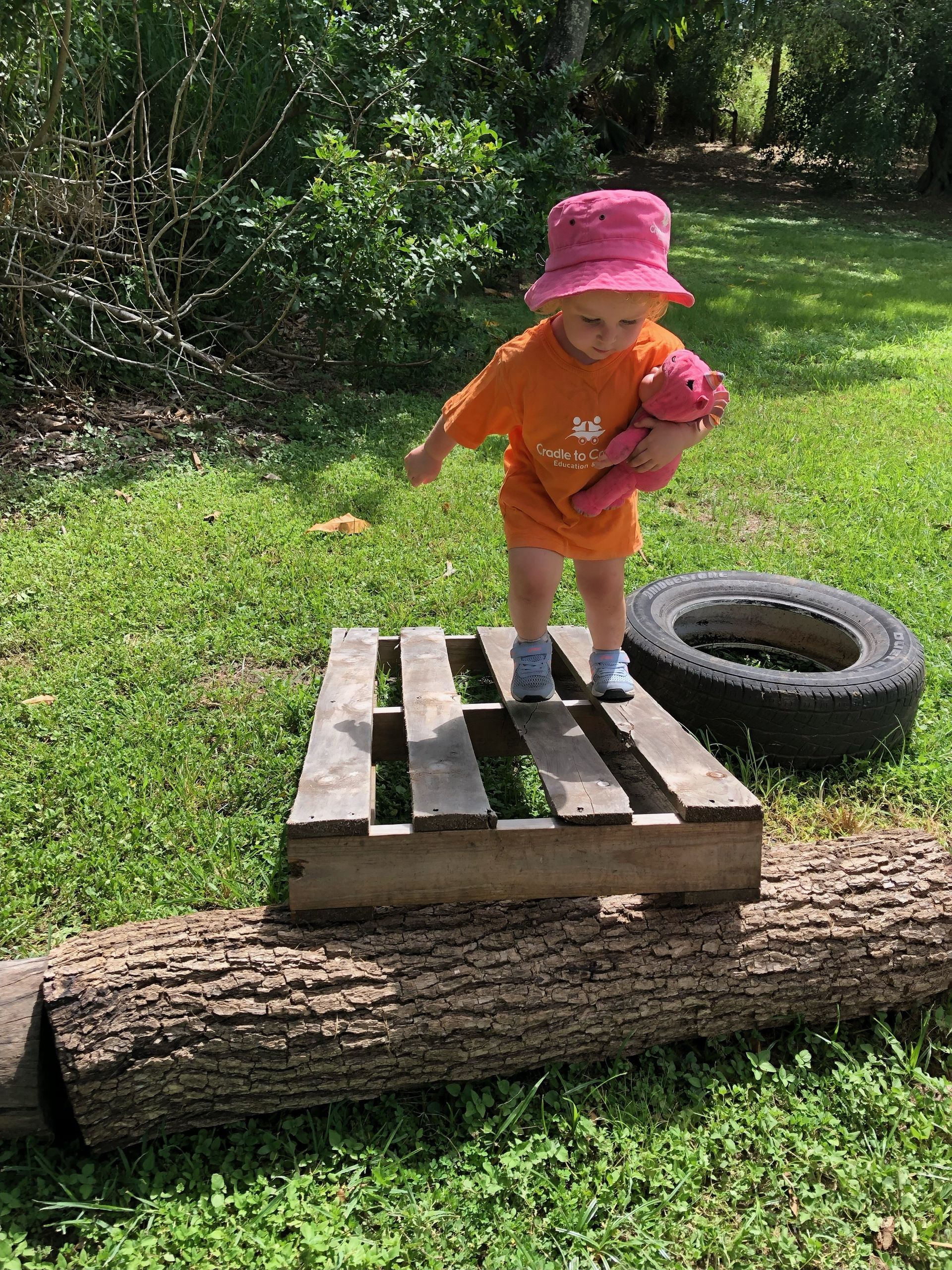 A Young Child is Climbing and Balancing on a Pallet – Bundaberg North, QLD - Cradle to Crayons Education & Care
