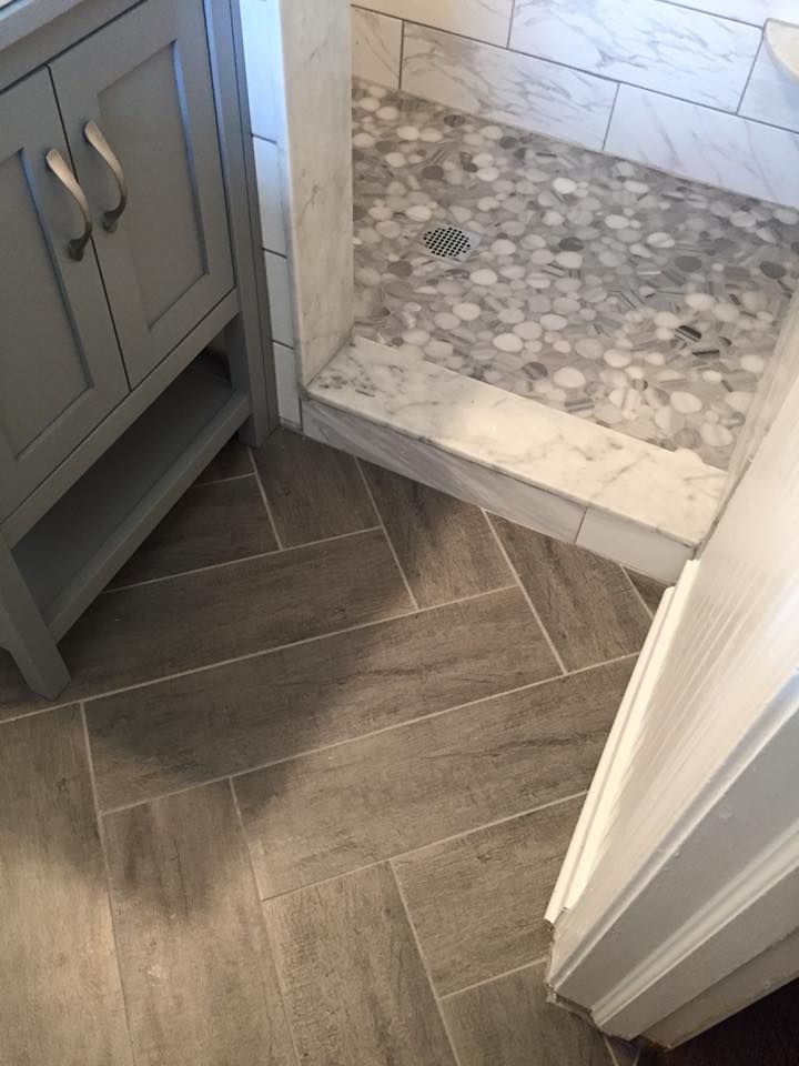 Gray bathroom with herringbone floor, marble shower, and gray vanity.