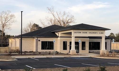 A small brick building with a sign reading “Behavioral Health Center” in a parking lot at dusk