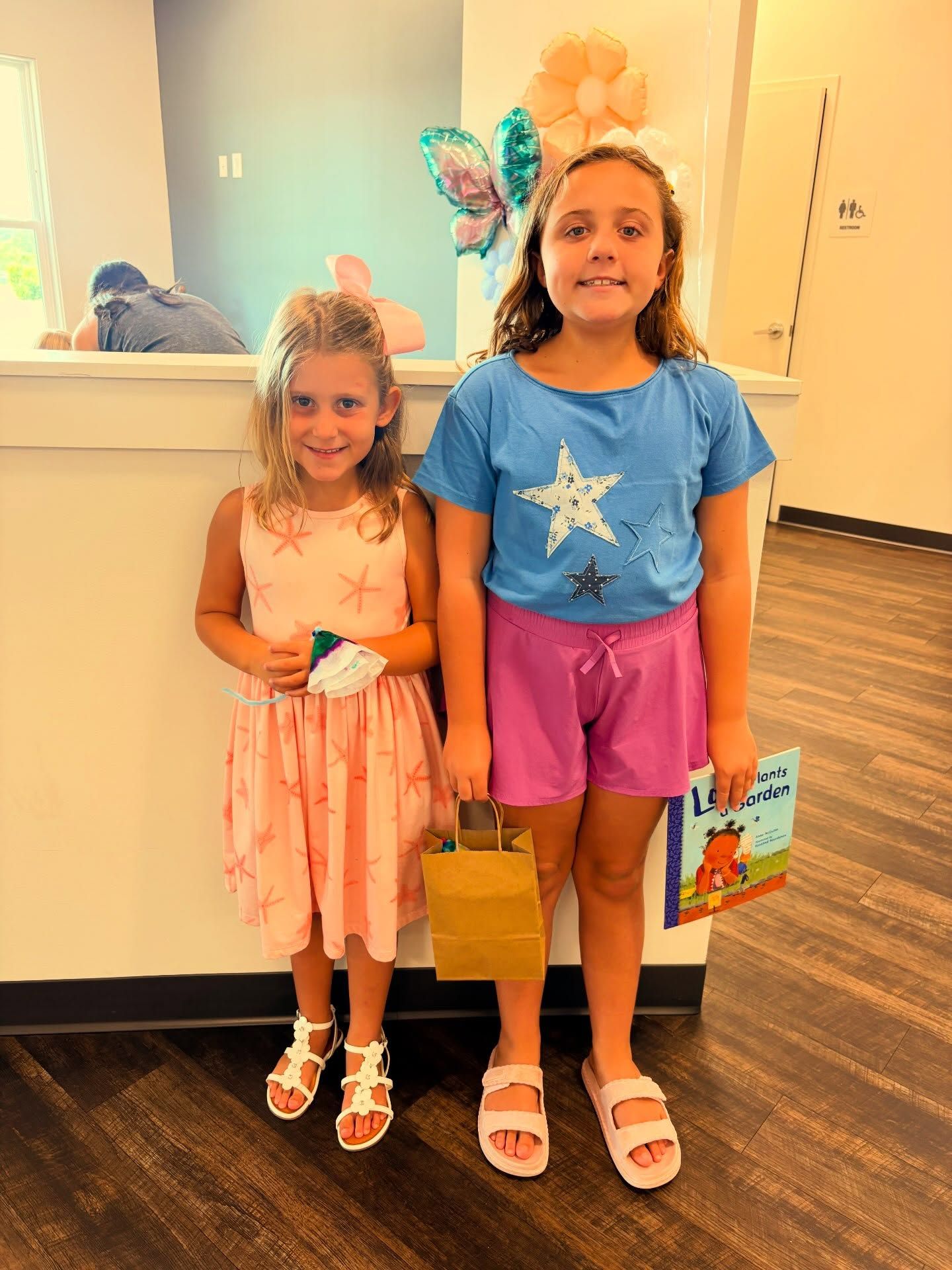Two young girls are wearing bright colors and standing in Eastern Shore Children's Clinic's medical office.