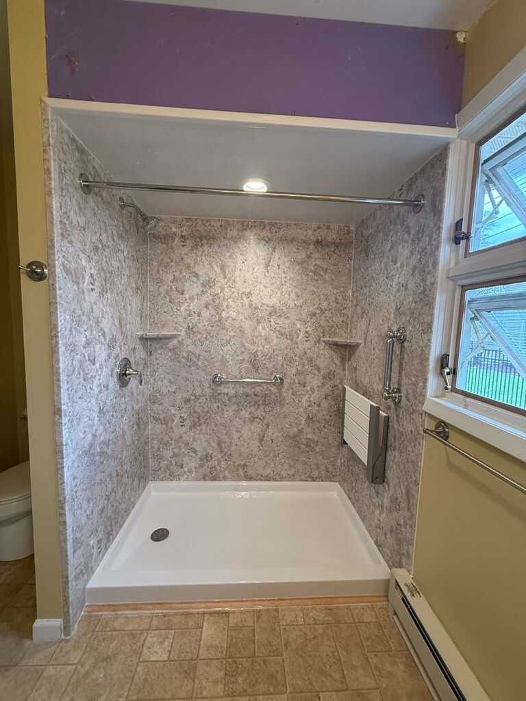 Newly renovated shower with textured gray walls and a white shower pan.