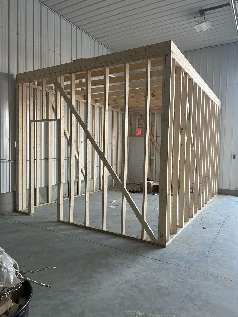 Wooden frame of a room constructed inside a larger building, door opening visible.