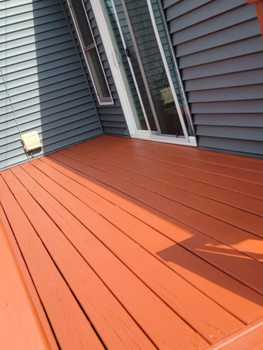 Newly painted orange deck with a blue-gray siding wall and glass sliding door.