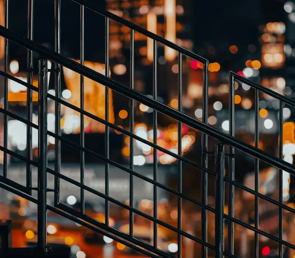 Metal staircase railing in front of blurred city lights at night