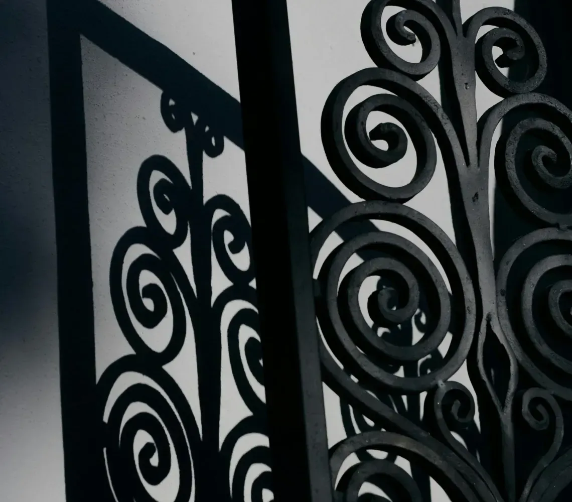 Black wrought-iron spiral gate or railing on a light gray wall