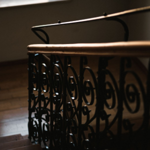 Decorative black wrought-iron stair railing lit by warm sunlight indoors