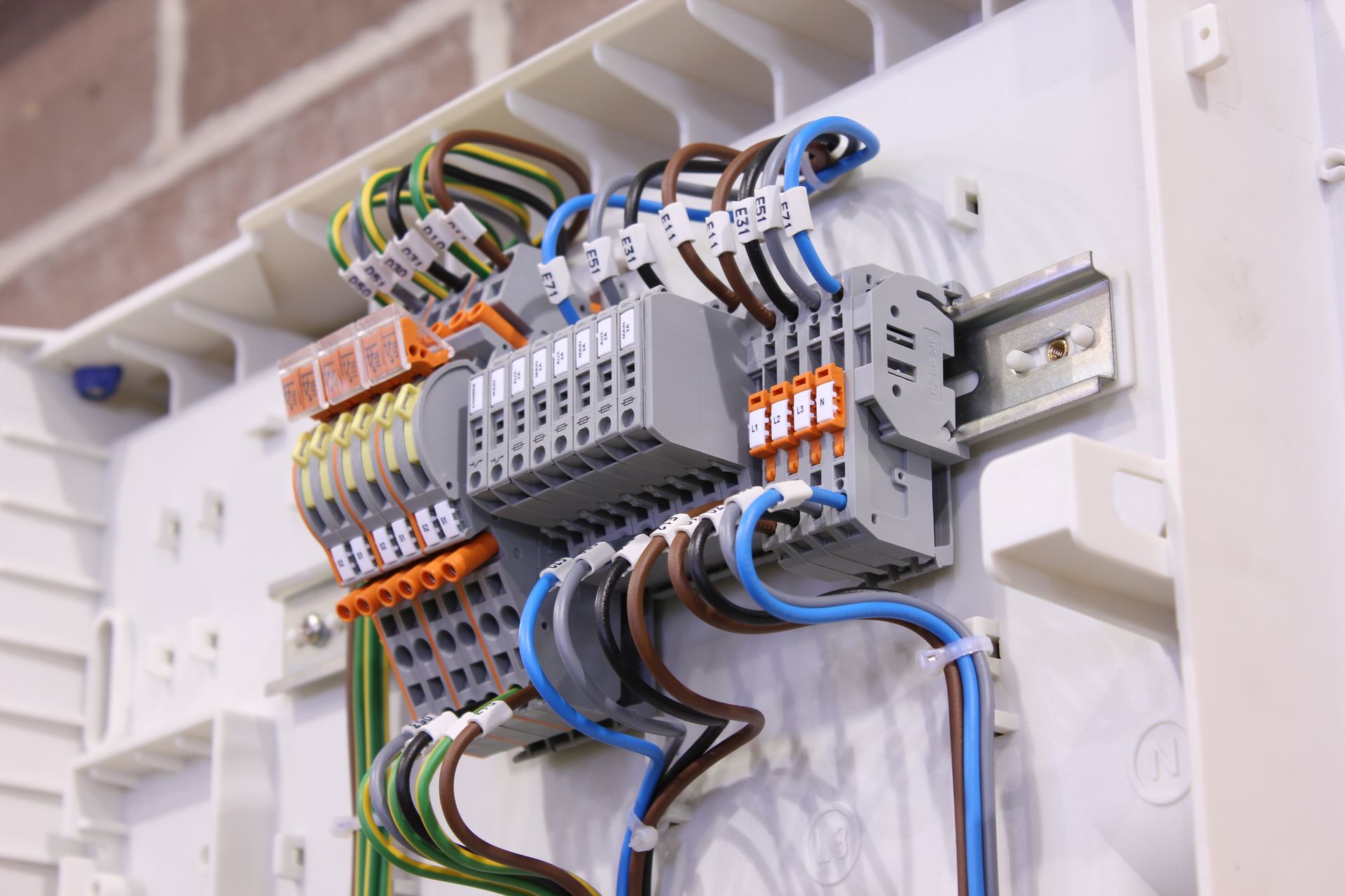 Electrical wiring and terminal blocks inside a wall-mounted network junction box with blue and green cables.