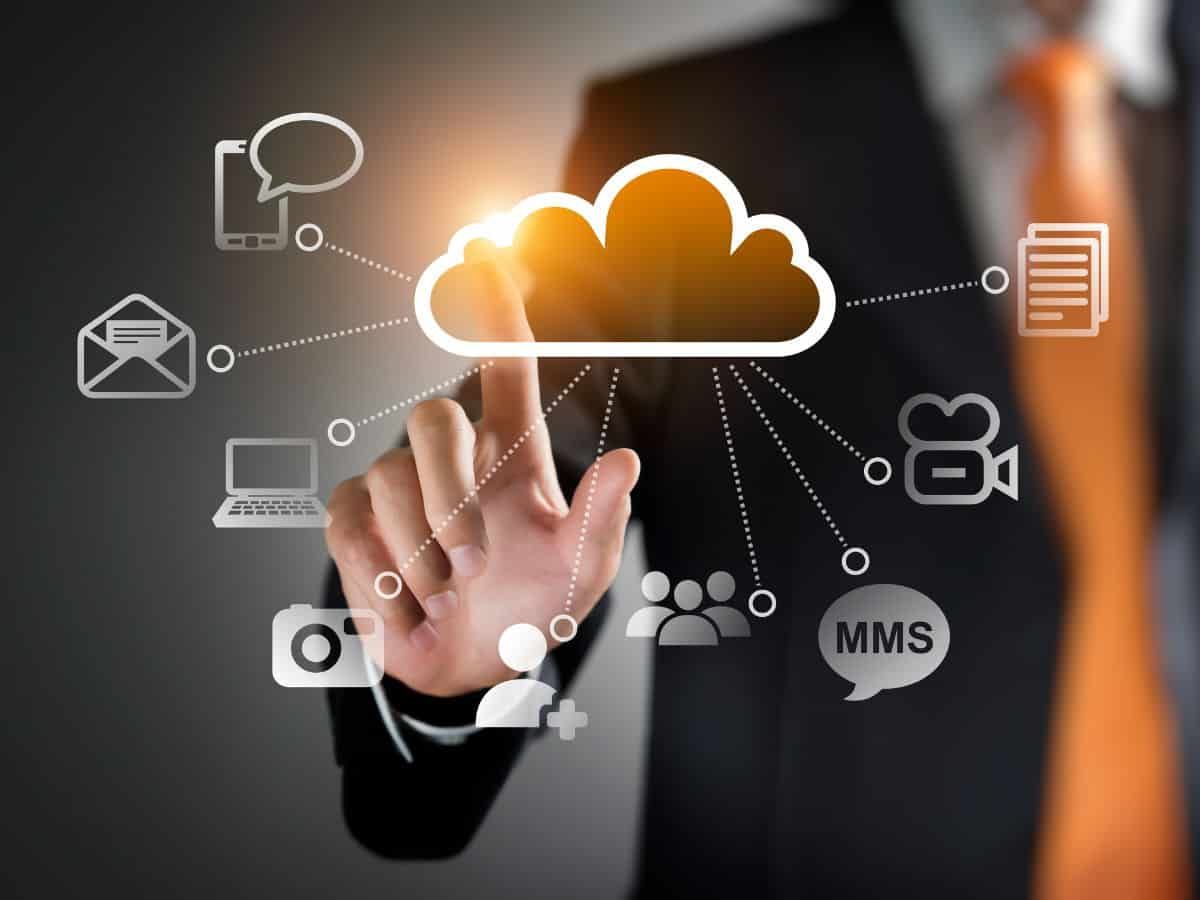 Hand touching glowing cloud icon with connected communication symbols on a dark background