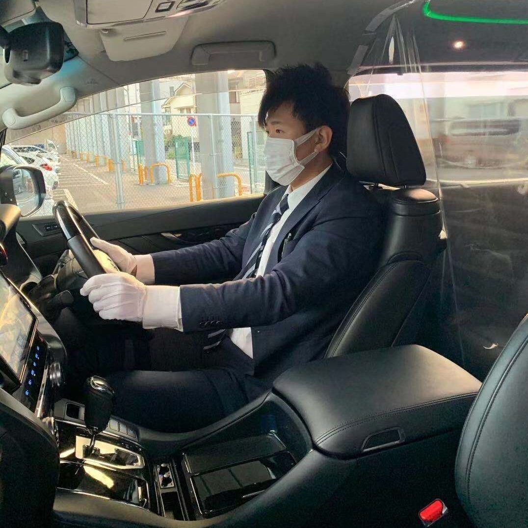 A man wearing a mask and gloves is driving a car