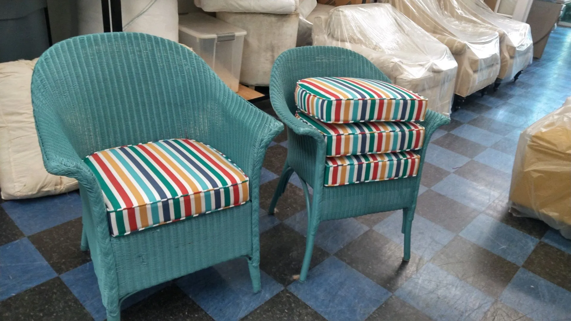Two turquoise wicker chairs with striped cushions in a warehouse-like room