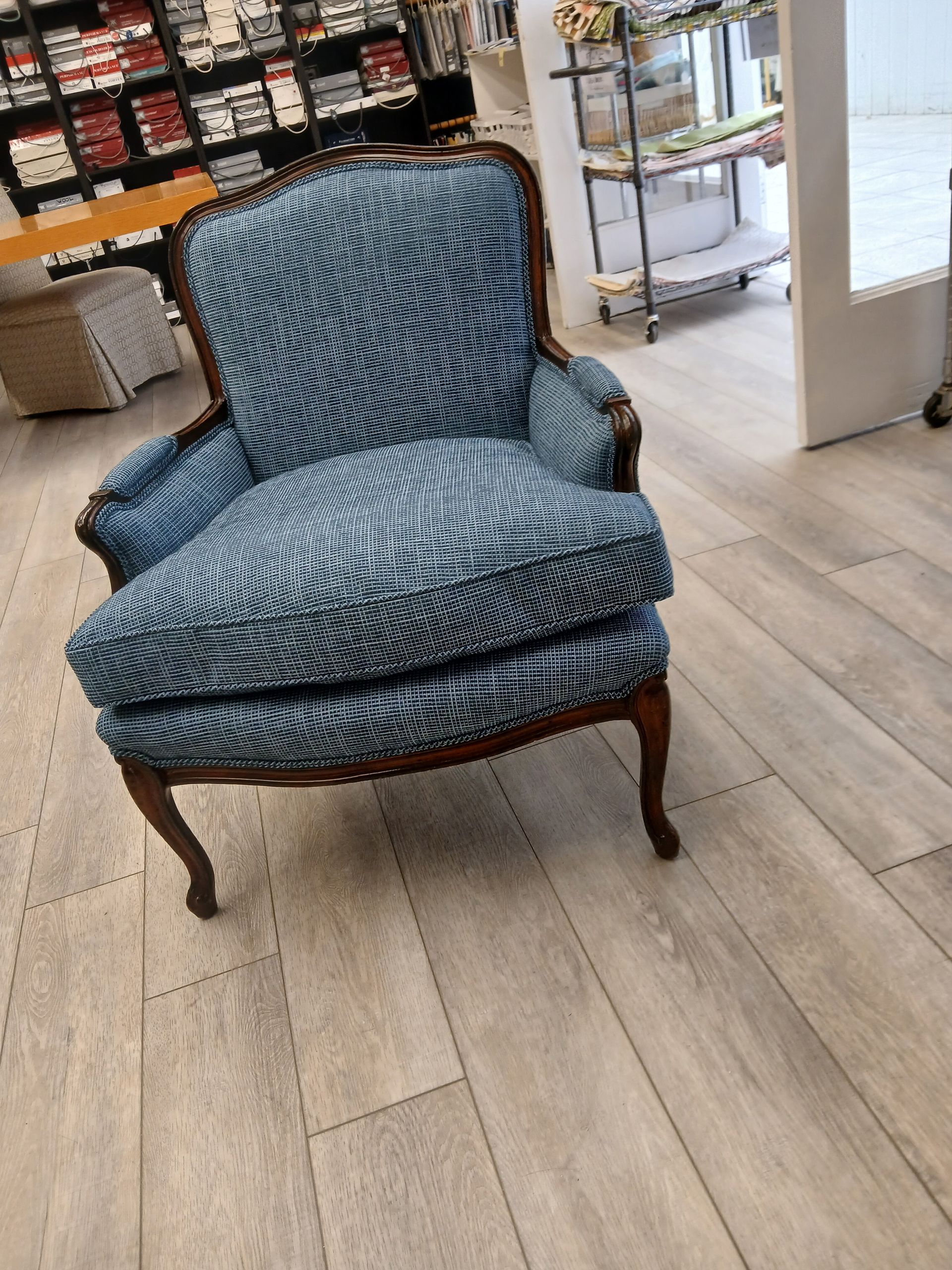 Blue patterned upholstered armchair in a furniture store with a folded cushion on the seat