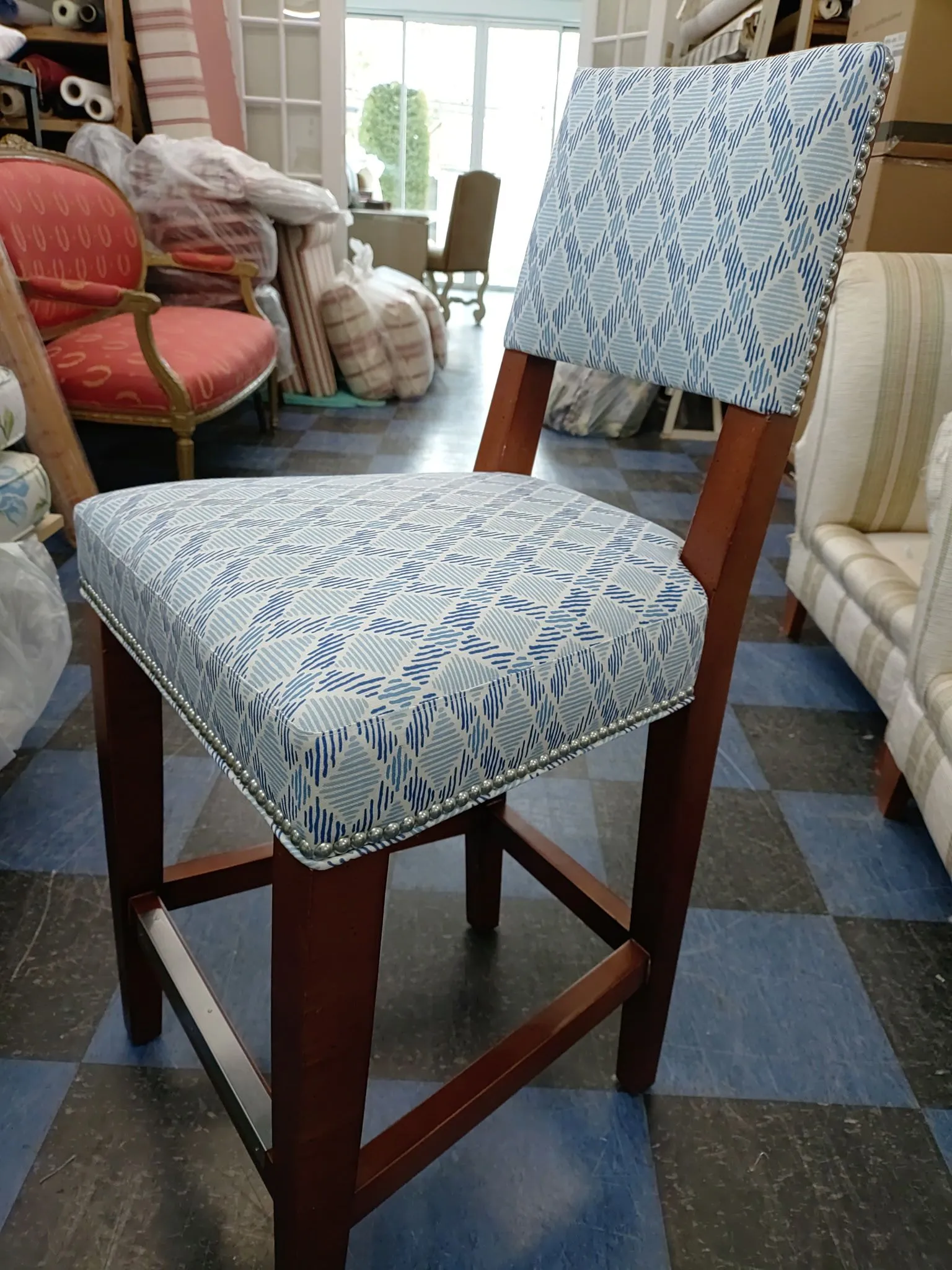 Blue patterned upholstered bar stool with dark wooden frame in a furniture store display