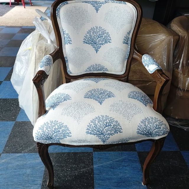 Vintage upholstered armchair with white and blue floral fabric and carved wooden frame