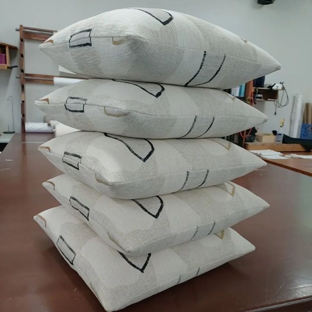 Four white fabric sandbags stacked on a wooden table in a workshop.