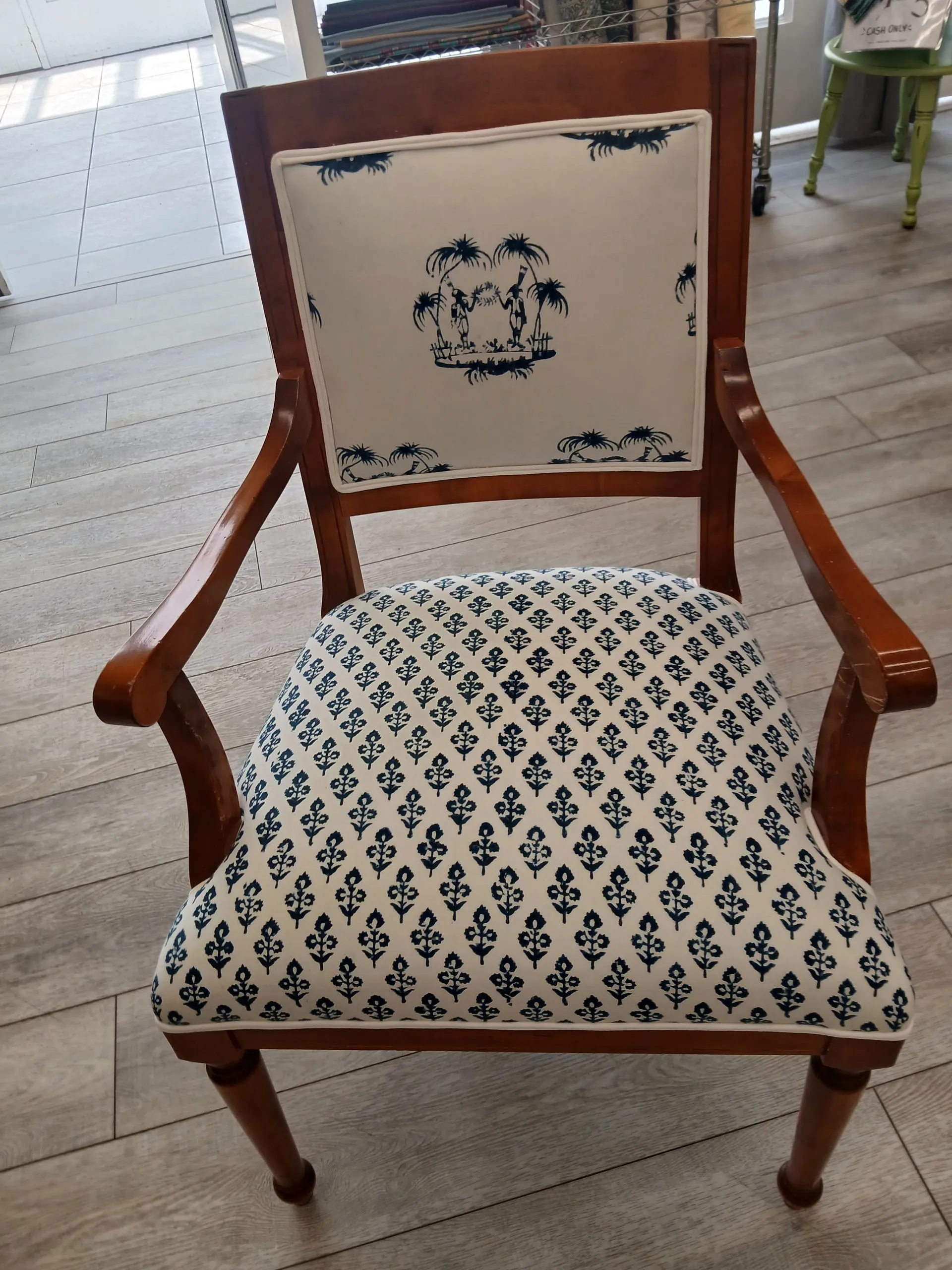 Vintage wooden armchair with cream upholstery and blue floral pattern in a bright room