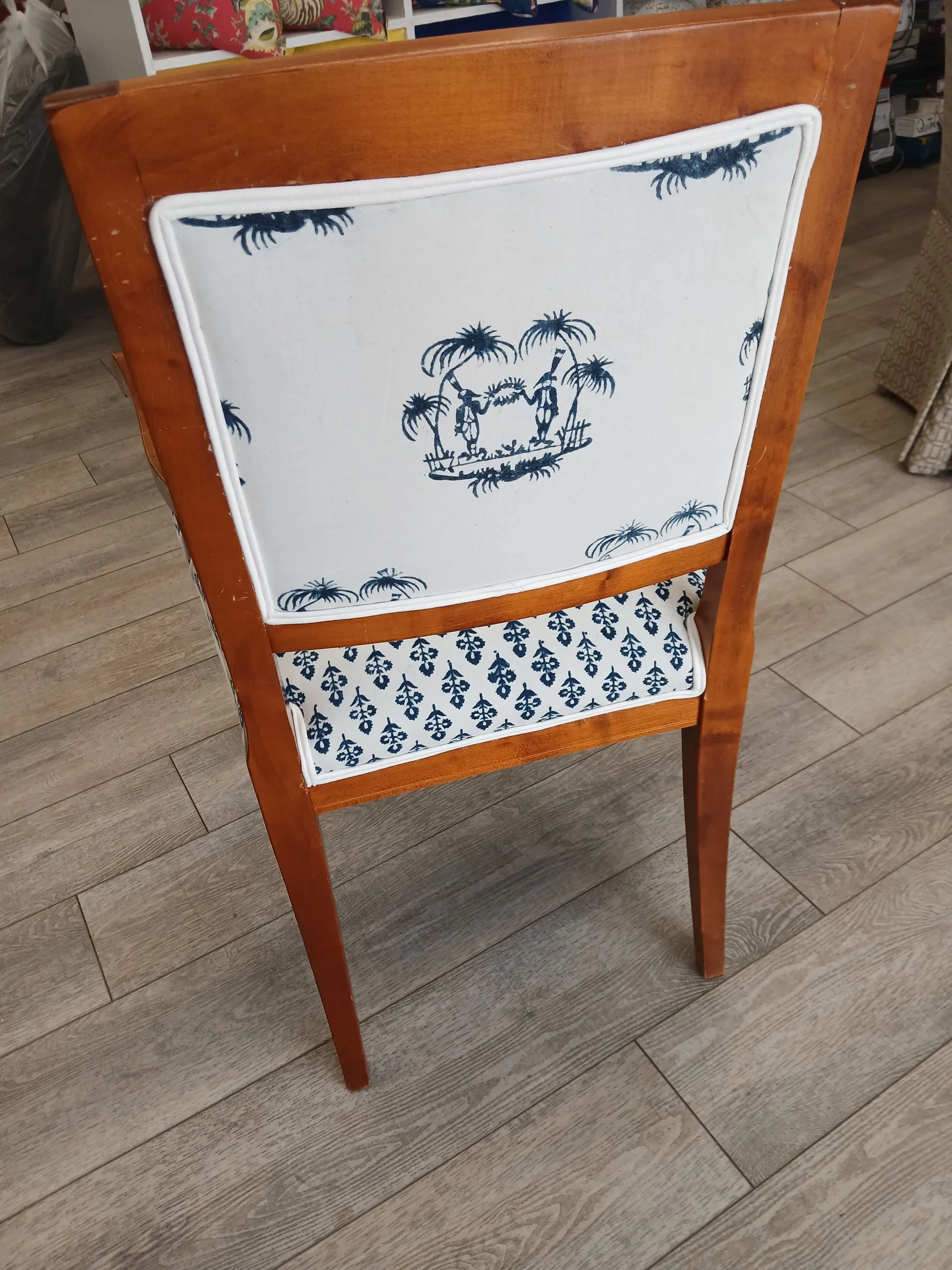Wooden chair with white-and-blue patterned upholstery on a tiled floor