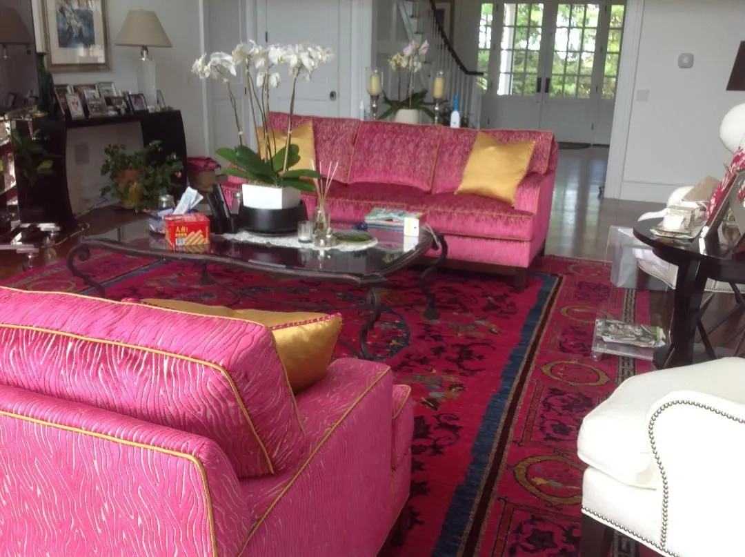 Bright living room with pink sofas, a glass coffee table, and a red patterned rug