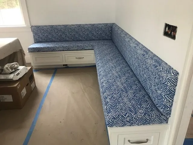 Blue patterned built-in banquette seating along a wall in a bright room, with storage drawers underneath.