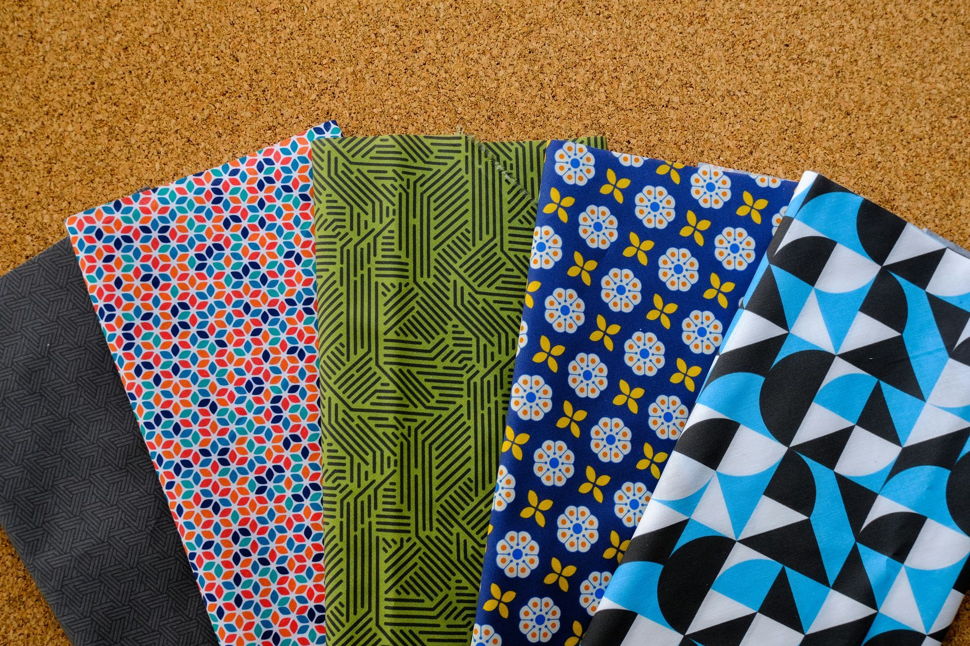 Five patterned fabric swatches fanned on a corkboard background