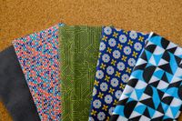 Five patterned fabric swatches fanned on a corkboard background