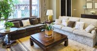 Bright living room with two sofas, wooden coffee table, lamp, and large windows