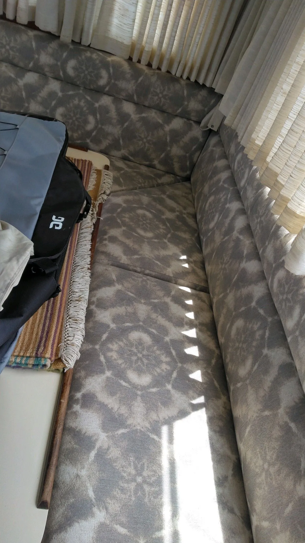 Sunlit gray upholstered corner sofa beside a curtain and low table in a living room