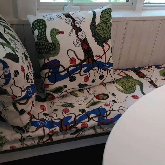 Patterned sofa by a window with white walls and a round white table in the foreground