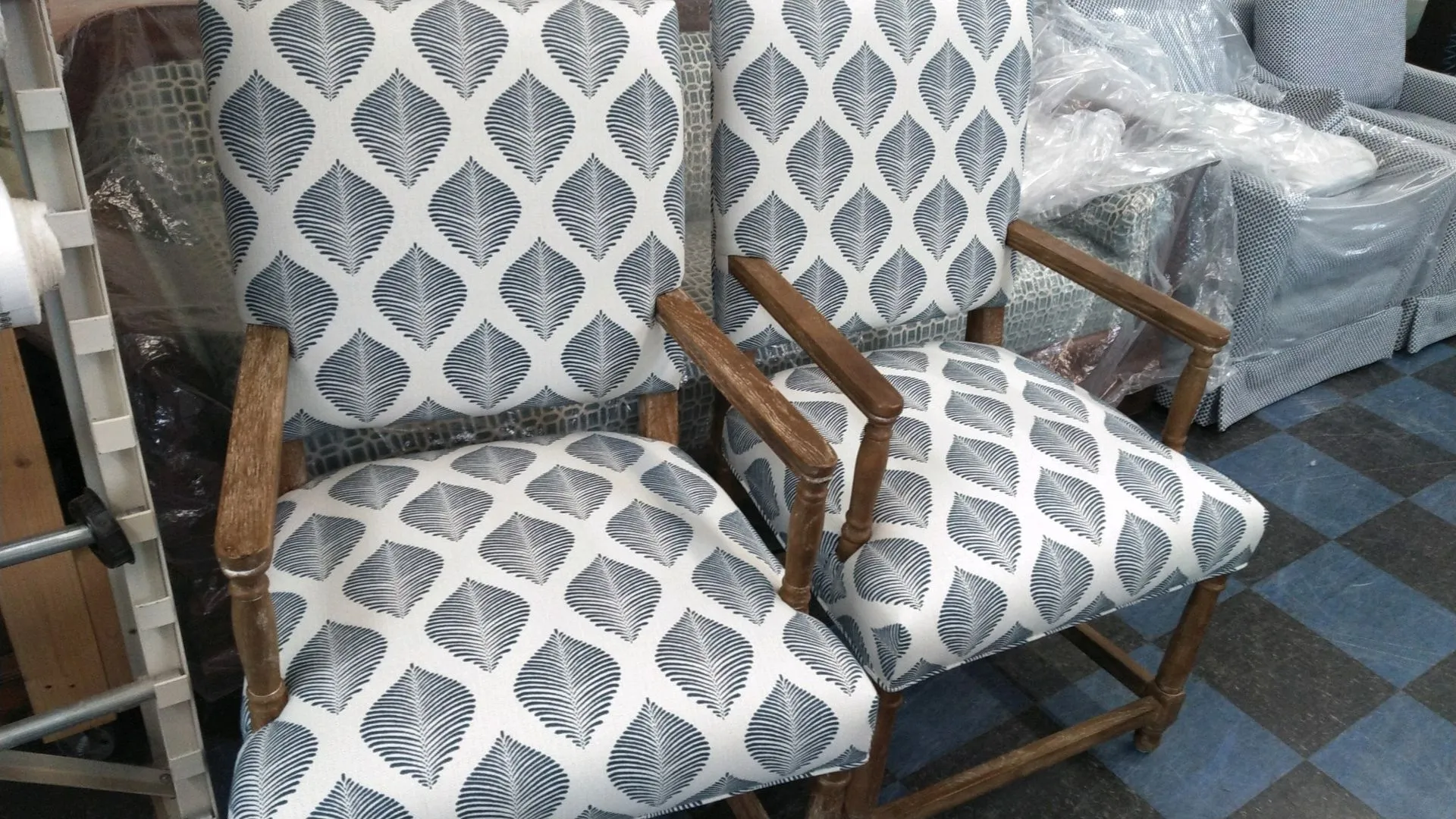 Two patterned armchairs with wooden arms, upholstered in gray and white, in a showroom.