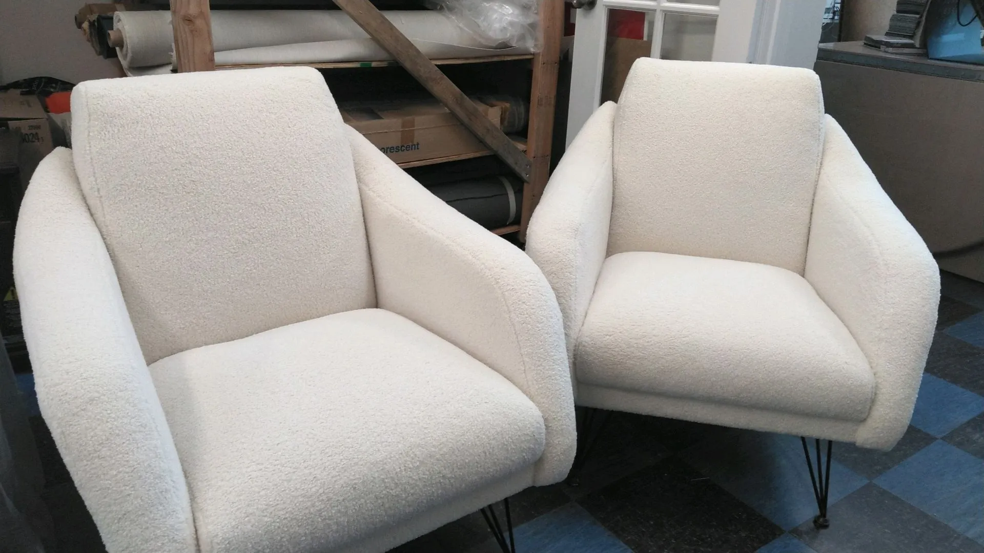 Two cream-colored upholstered armchairs with dark legs in a furniture showroom.