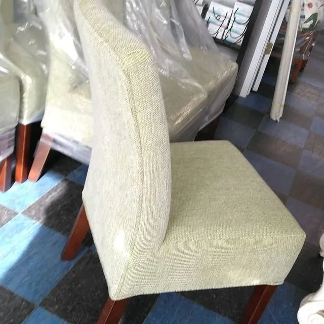 Beige upholstered dining chair with wooden legs on a checkered floor in a furniture store