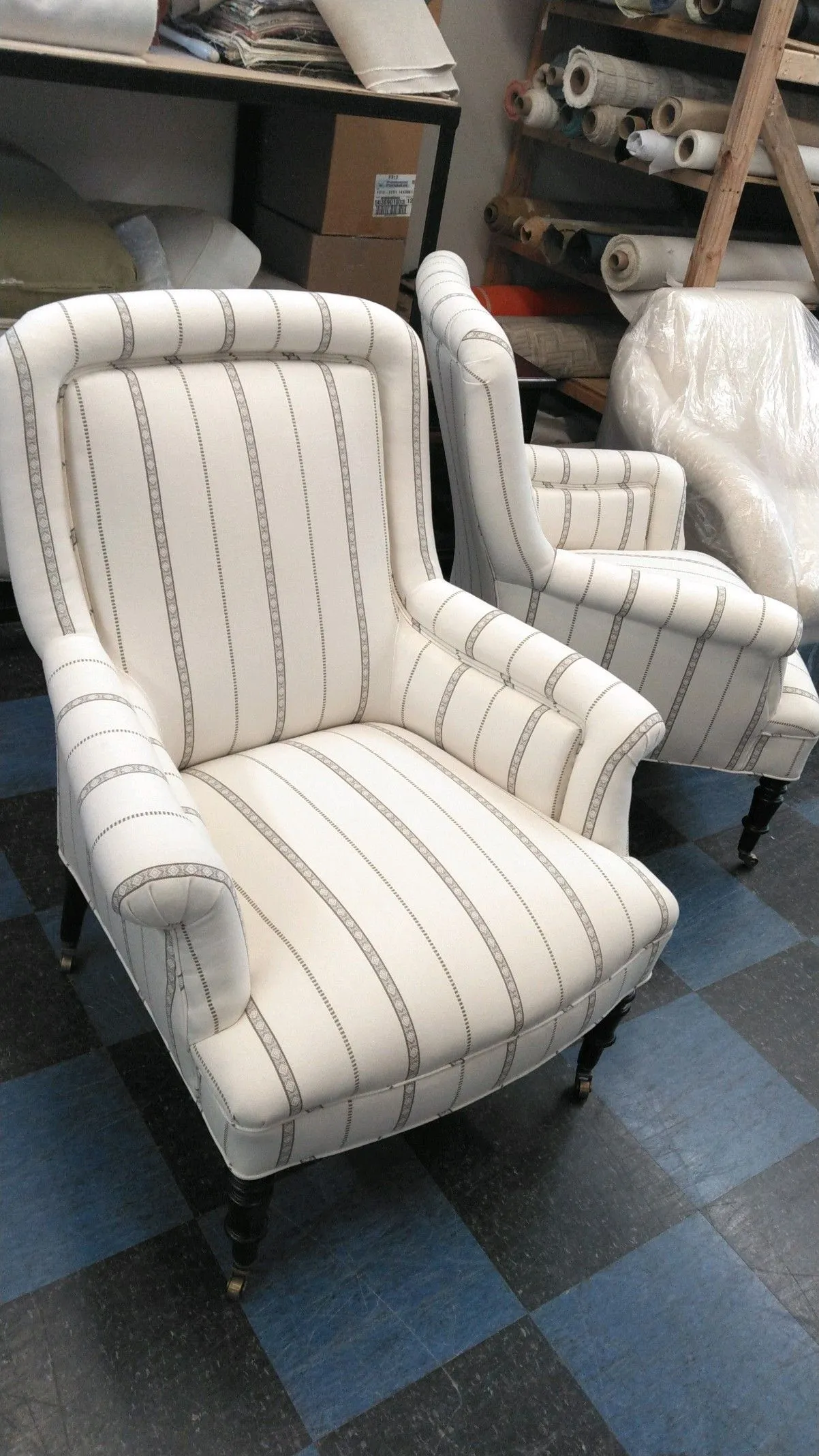 Striped upholstered armchair in a furniture workshop, with another chair behind it
