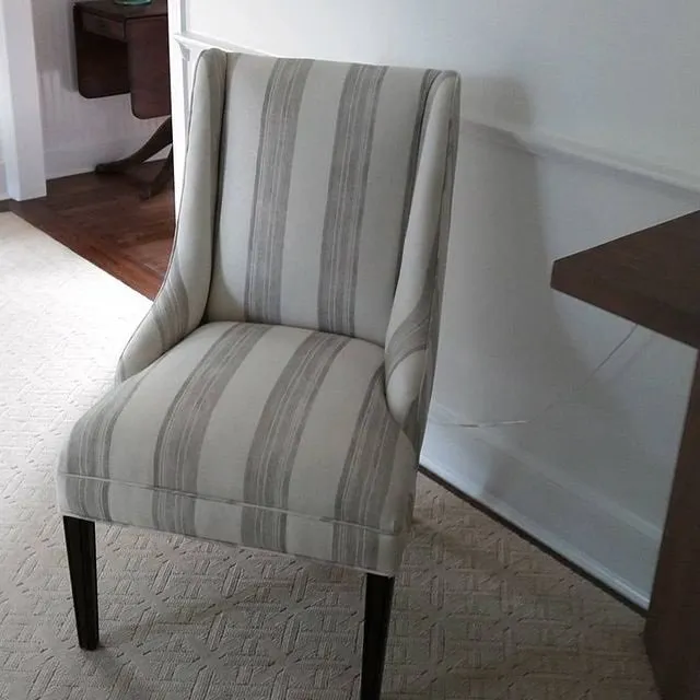 Striped upholstered accent chair with dark legs in a carpeted room
