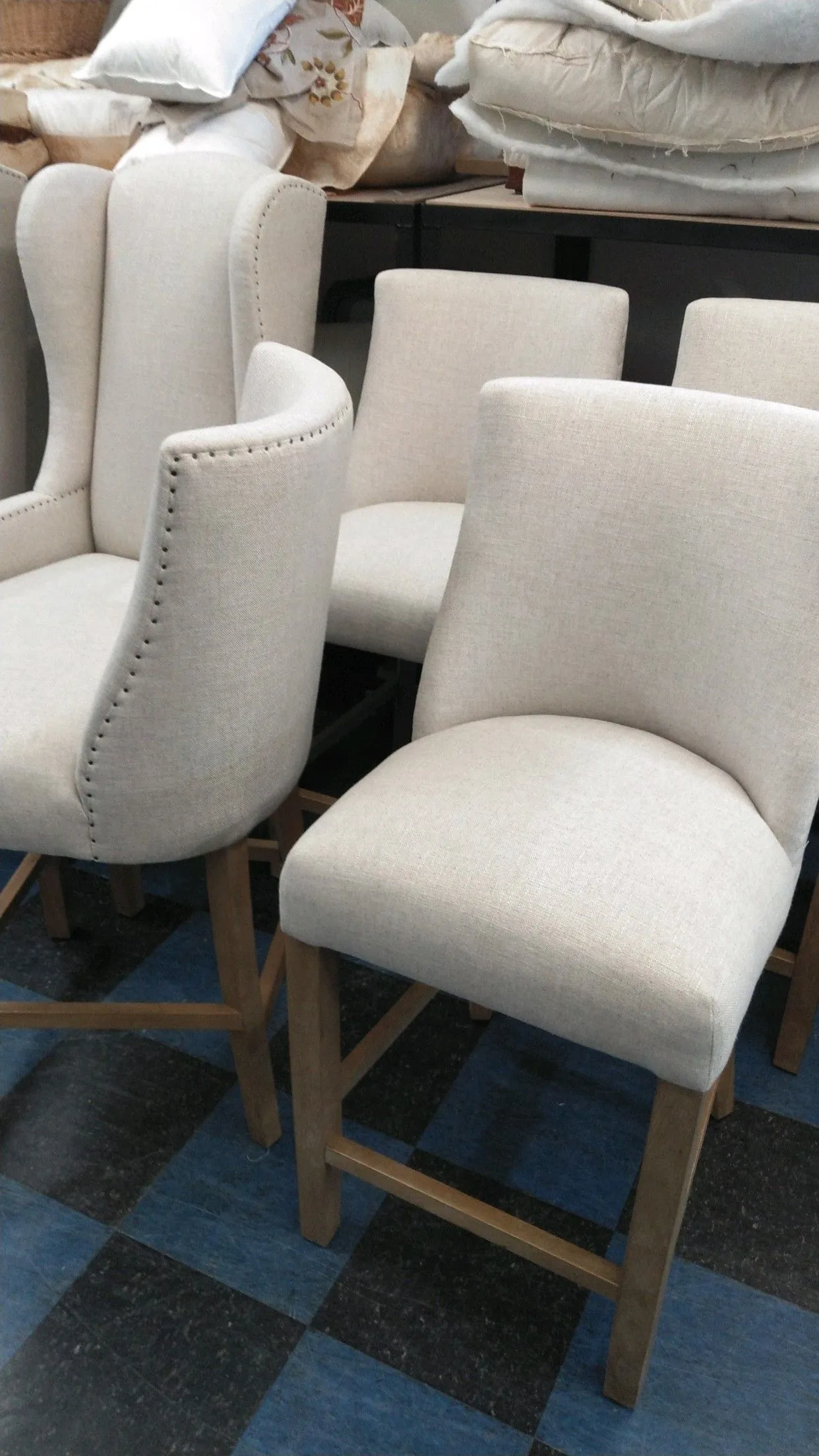Two cream upholstered dining chairs with wooden legs in a workshop or storage area.