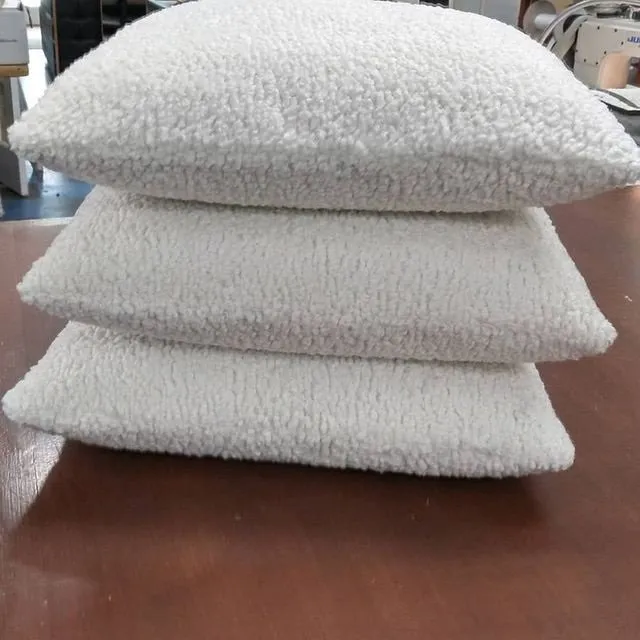 Three stacked white woven cushions on a wooden table