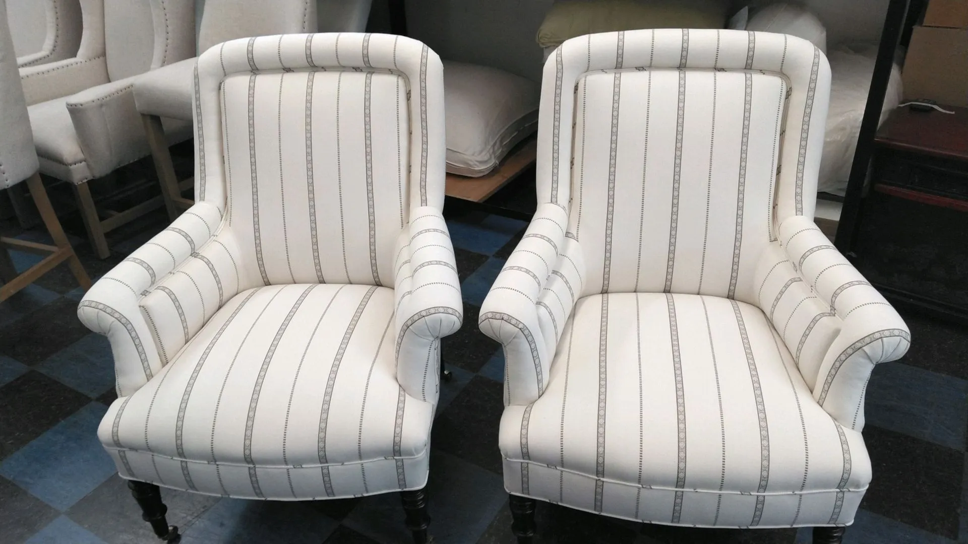 Two striped white upholstered armchairs side by side in a furniture showroom