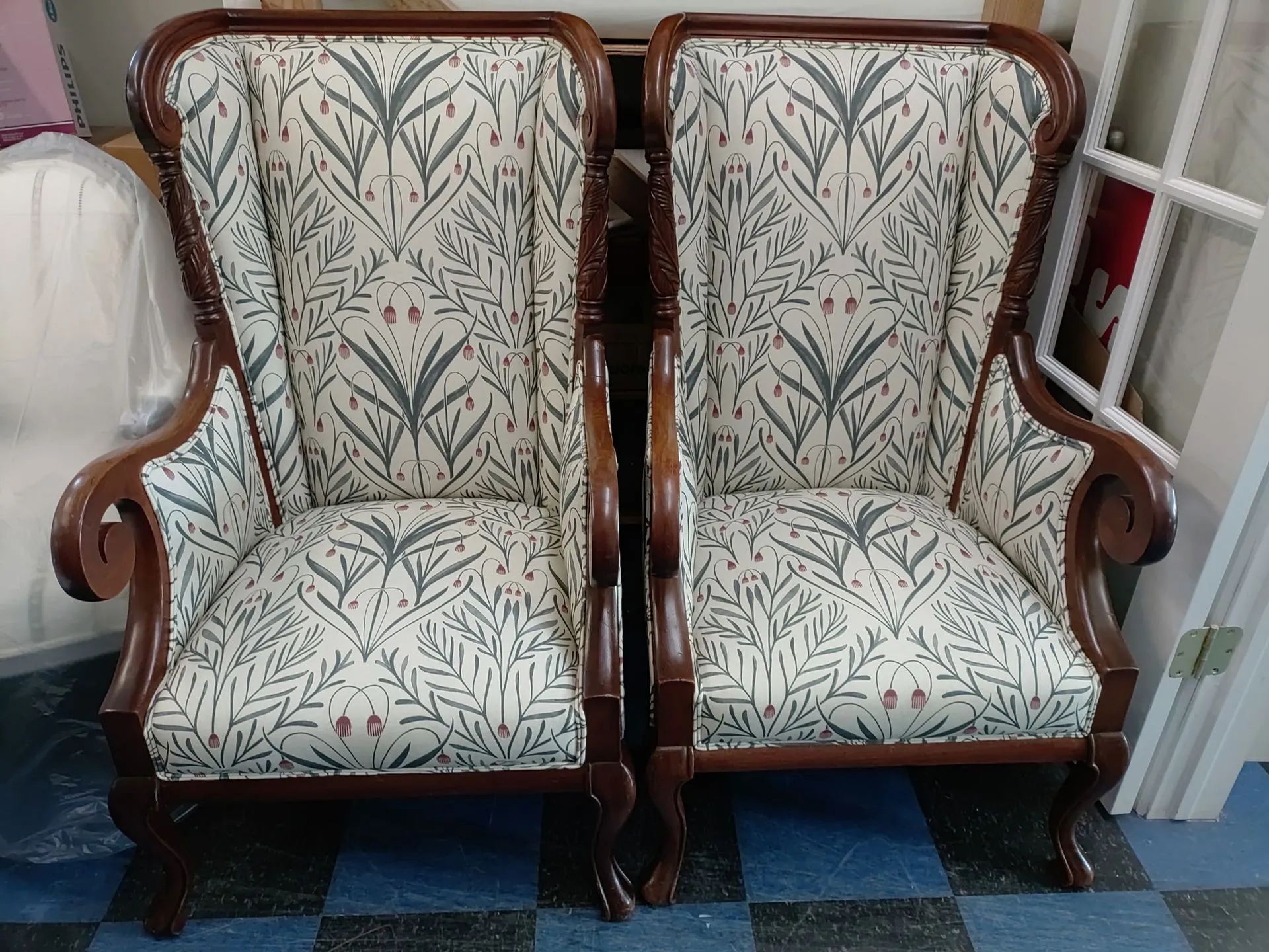 Two upholstered vintage wooden armchairs with floral fabric, side by side indoors