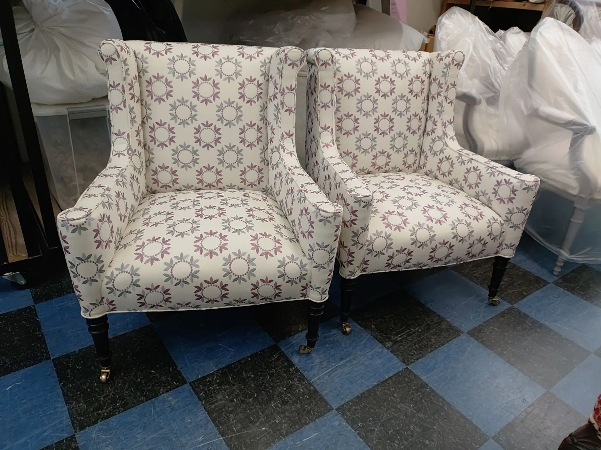 Two patterned upholstered armchairs side by side on a black-and-blue checkered floor