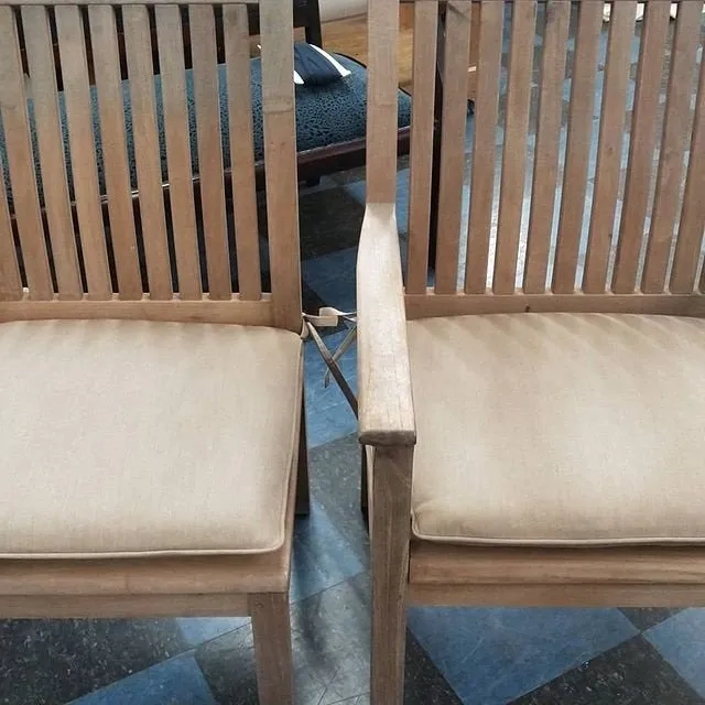Two wooden dining chairs with beige cushions facing a blue-gray tiled floor