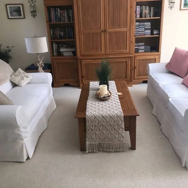 Cozy living room with two white sofas, wooden coffee table, and large wooden cabinet.