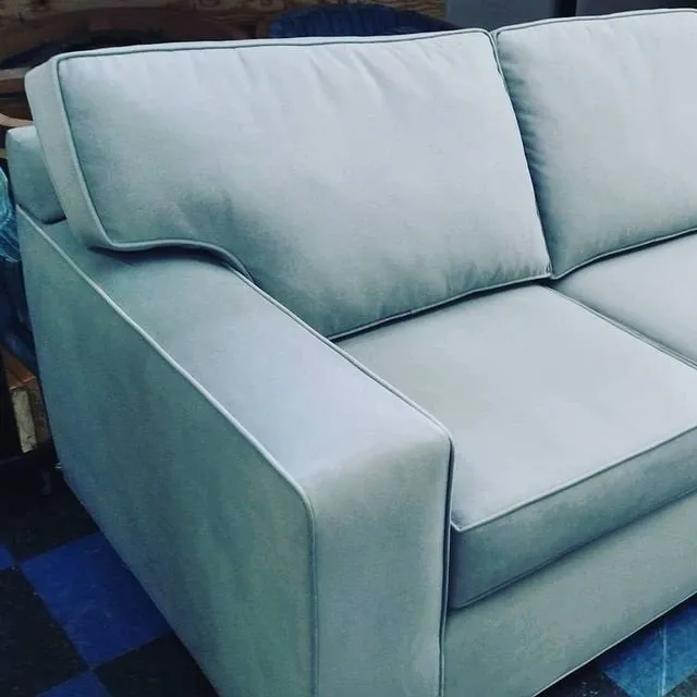 Light blue upholstered sofa with cushioned arms and backrest in a room setting