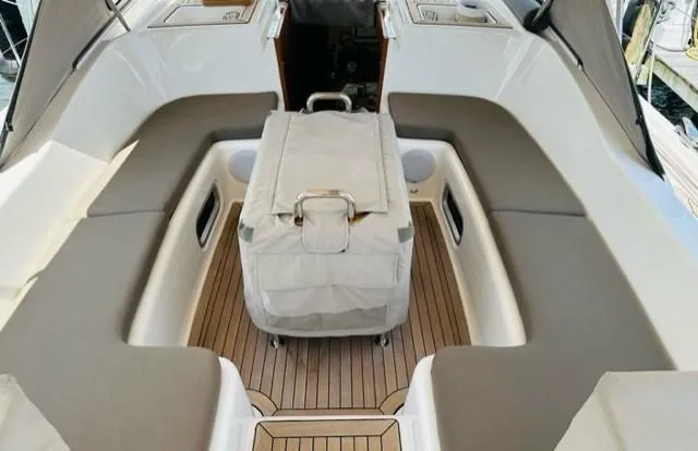 Boat cockpit with white cushioned seating and teak flooring, centered on a covered console seat