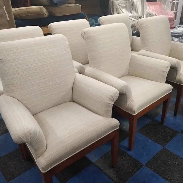 Row of beige upholstered armchairs with wooden legs on a blue-and-black checkered floor
