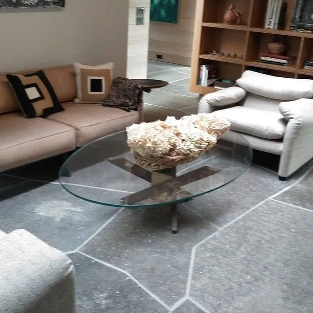 Modern living room with beige and white chairs, glass coffee table, and a decorative centerpiece.