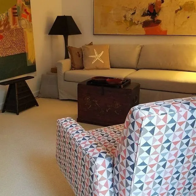 Cozy living room with beige sofa, patterned chair, floor lamp, and wall art