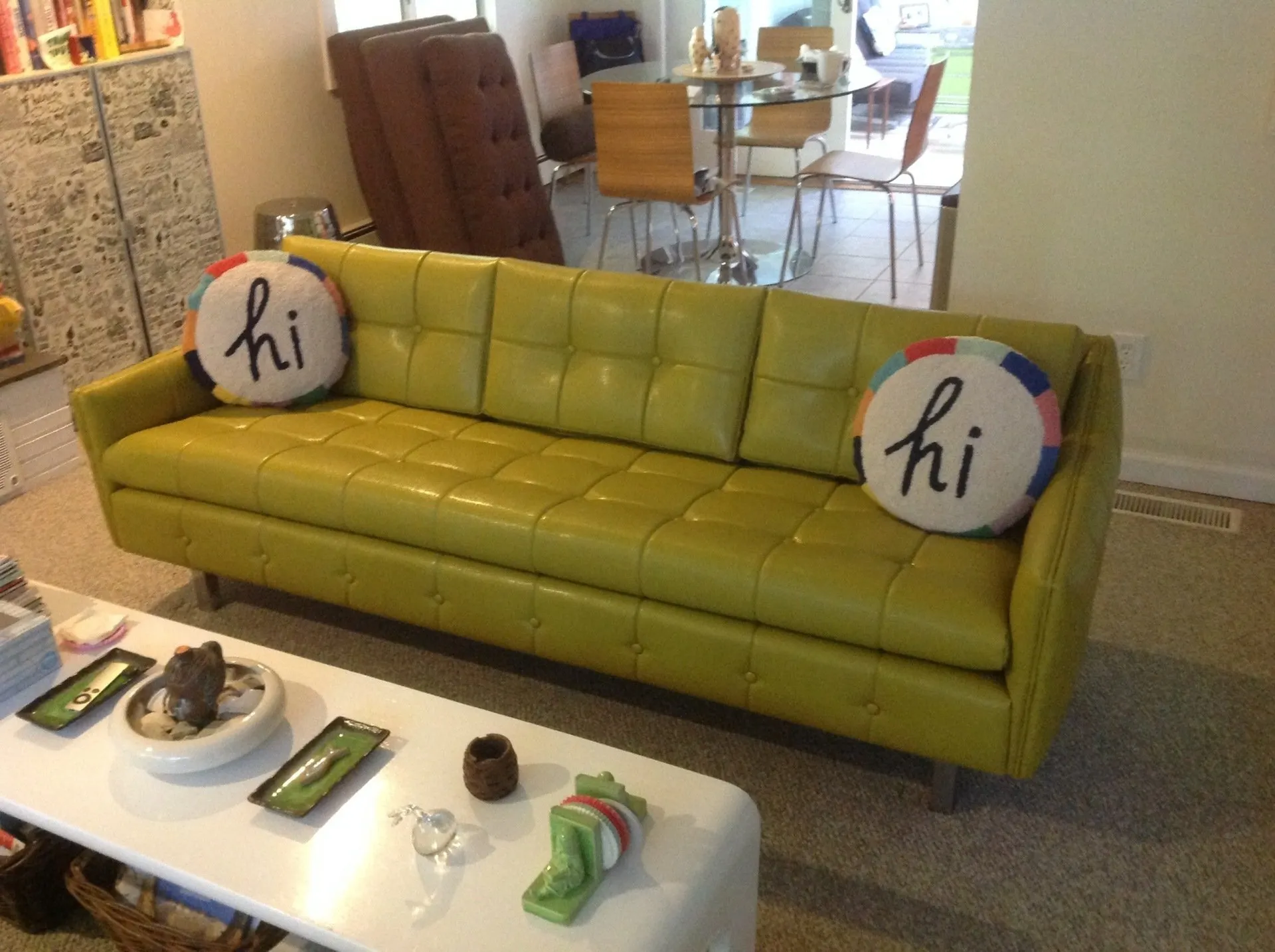 Yellow sofa with two “hi” pillows in a bright living room and a white coffee table in front