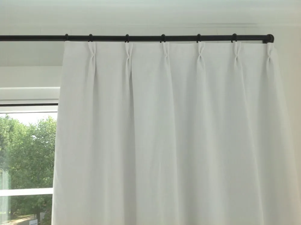 White curtains hanging from a black curtain rod beside a window and sliding glass door