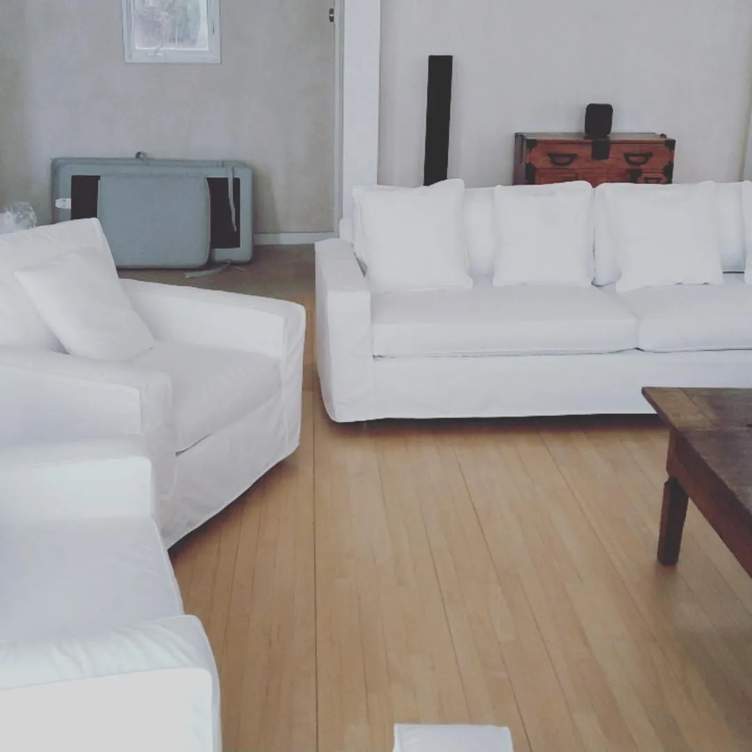 Bright living room with white sofas, wooden floor, and a coffee table.