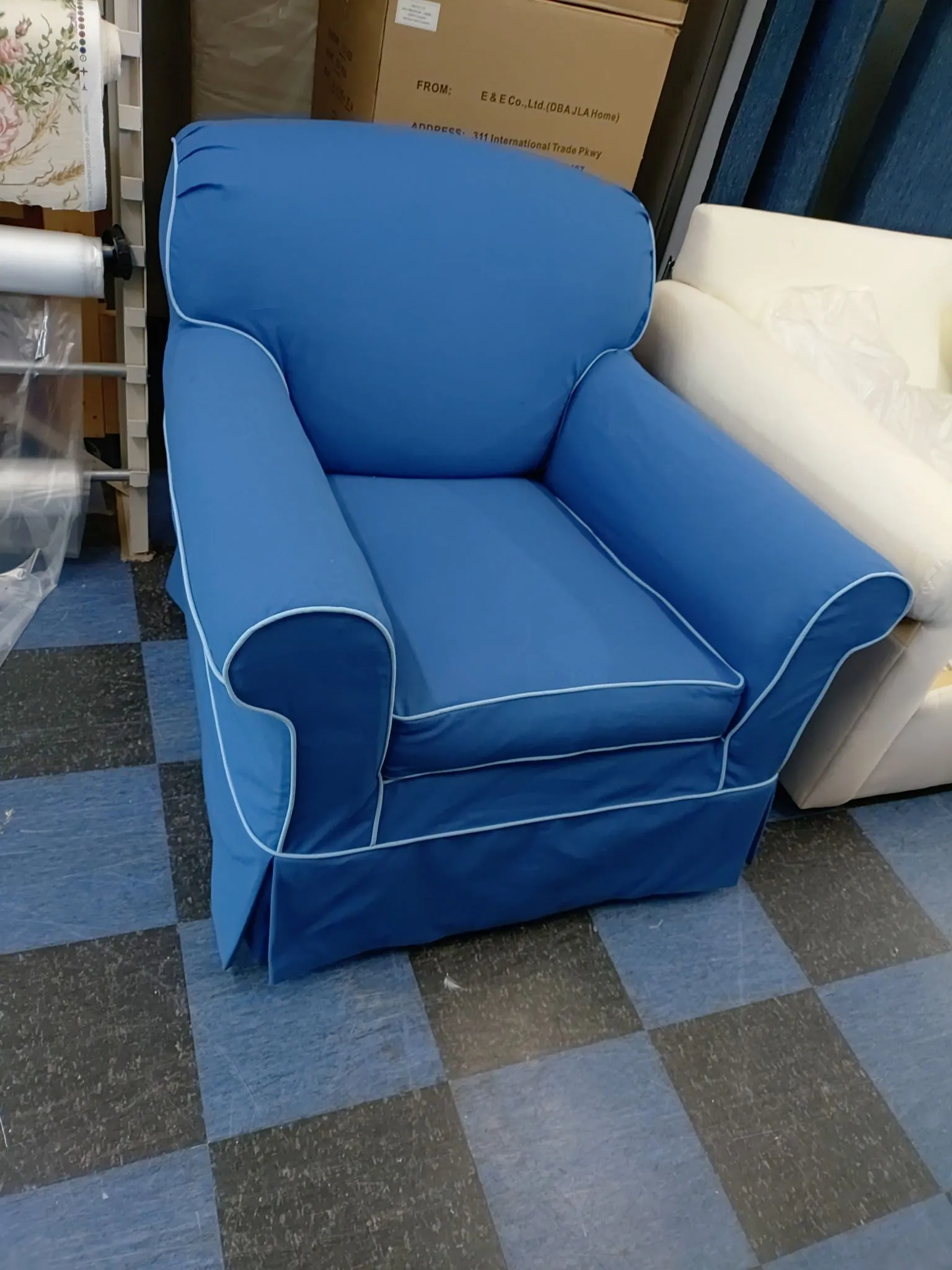 Blue upholstered armchair with white trim on a checkered floor in a storage room
