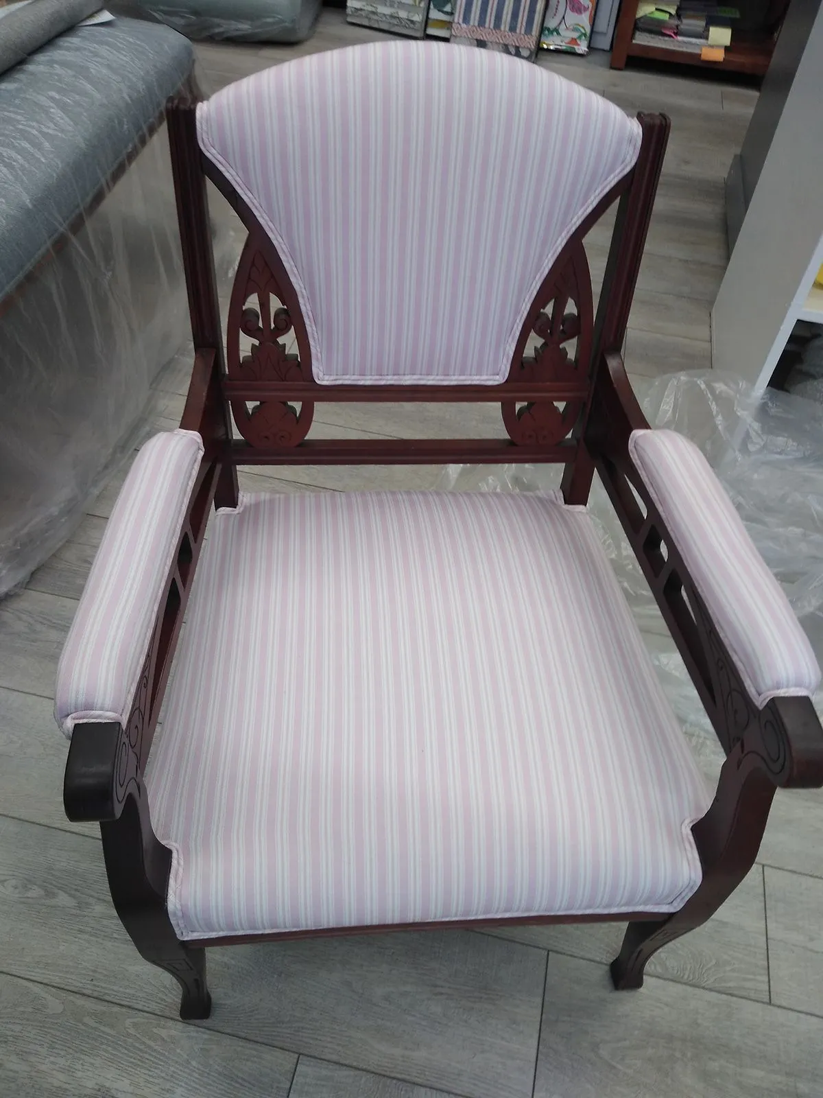 Striped upholstered armchair with dark wood frame and curved arms, indoors on a rug